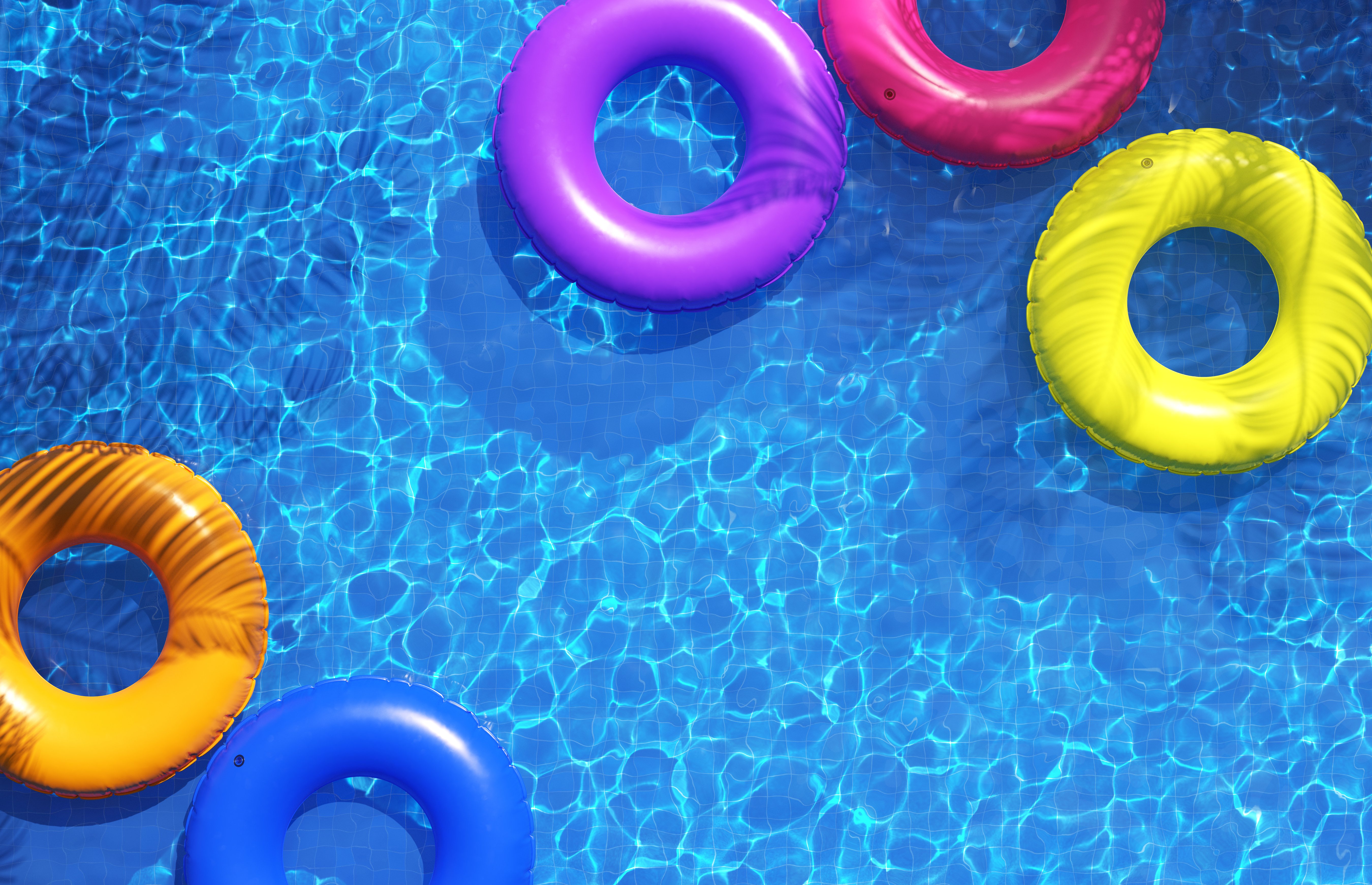 Multi-colored swimming rings in swimming pool. Pool party, summer background. Top view